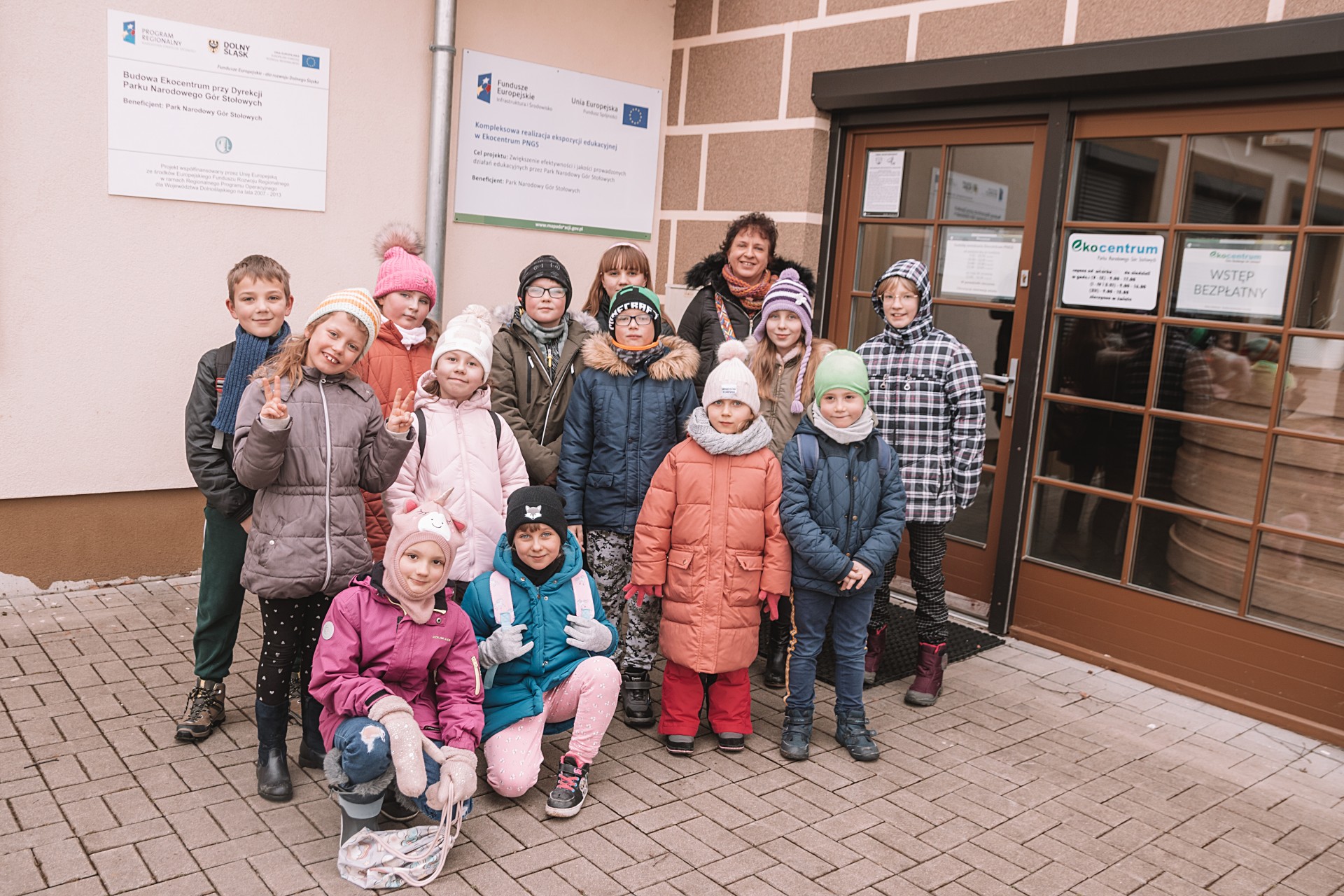 Grupa dzieci stojących przed wejściem do budynku
