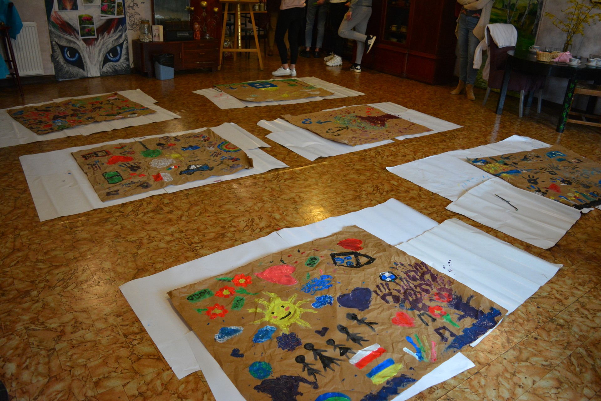 Warsztaty plastyczne – prace namalowane przez uczniów rękami na szarym papierze.