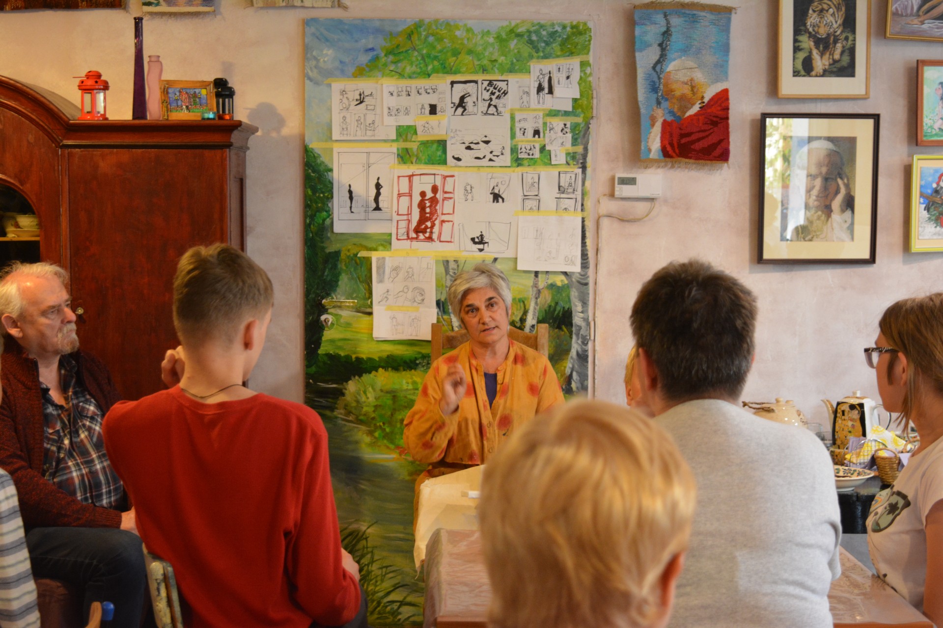 : Uczestnicy warsztatów słuchają wprowadzenia prowadzącej na temat techniki malarstwa olejnego.