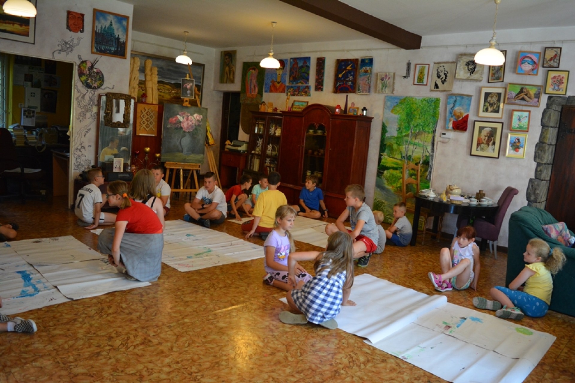 dzieci malują wspólnie palcami obrazki na szarym papierze.