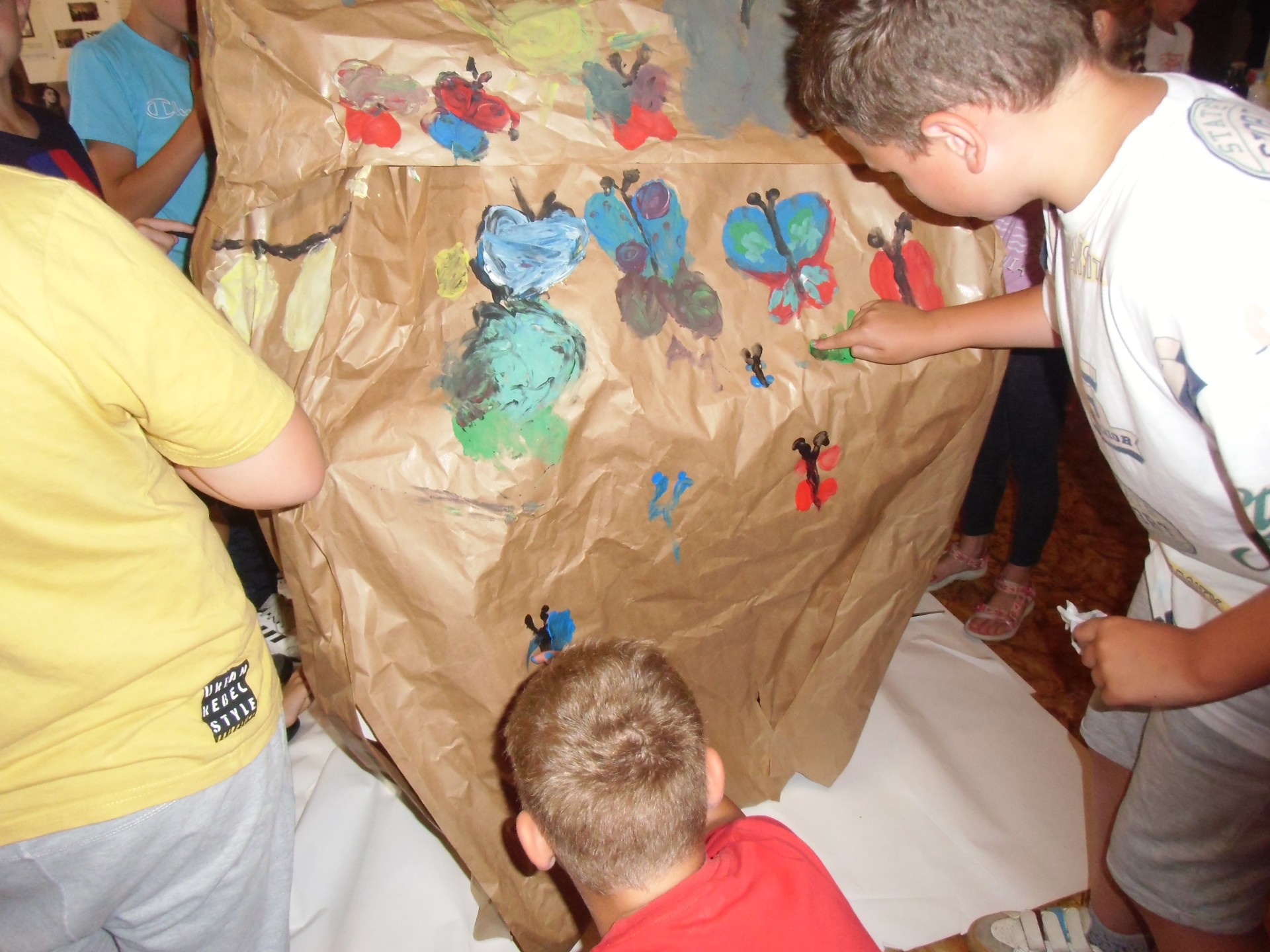 Dzieci malują rękami na skałach zrobionych z szarego papieru