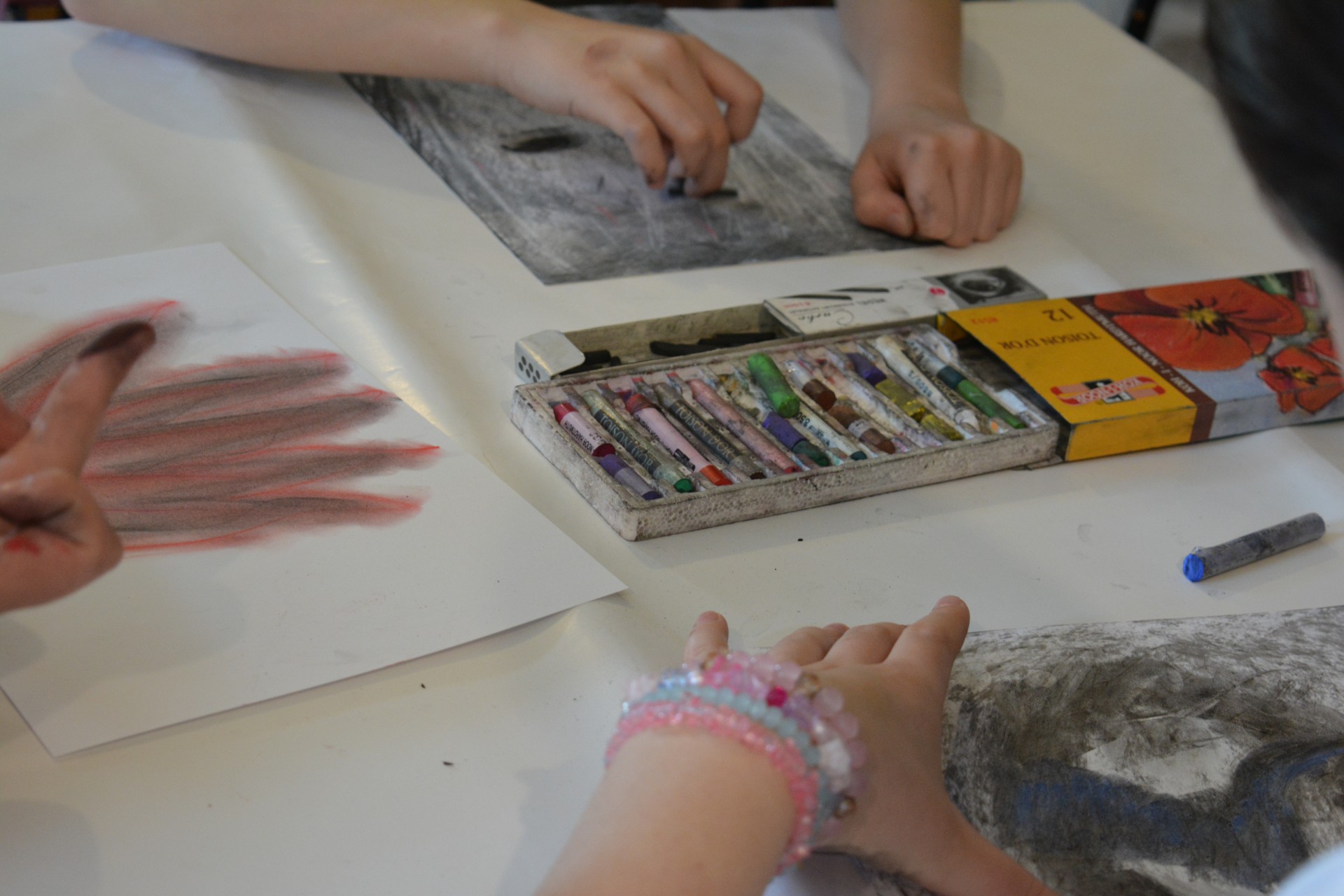 Uczestnicy warsztatów rysują węglem oraz pastelami