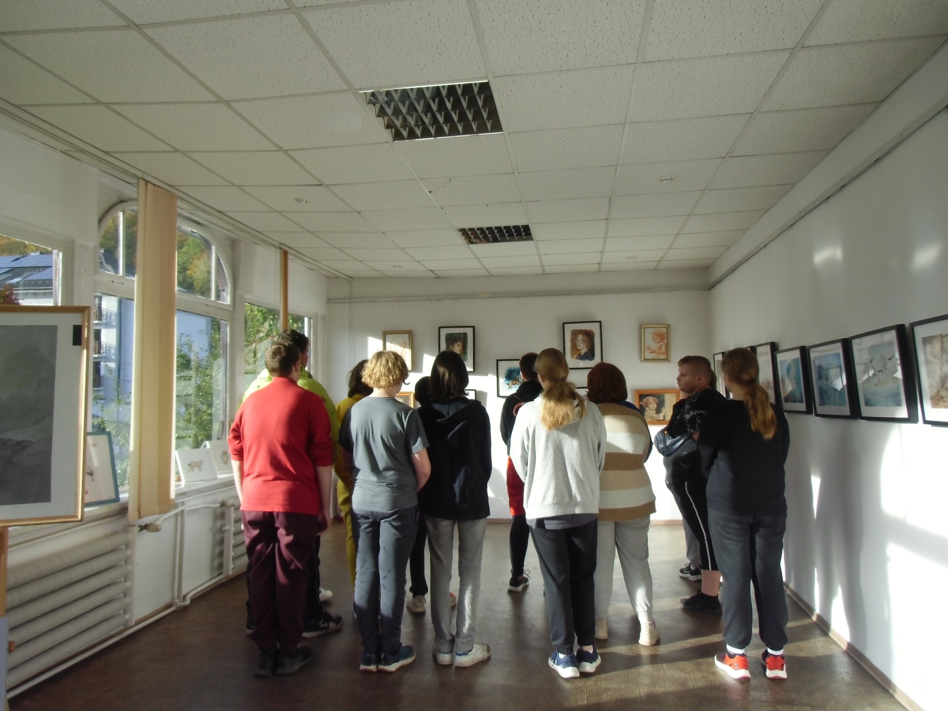 Grupa młodzieży zwiedza wystawę Natalii Brzezińskiej.