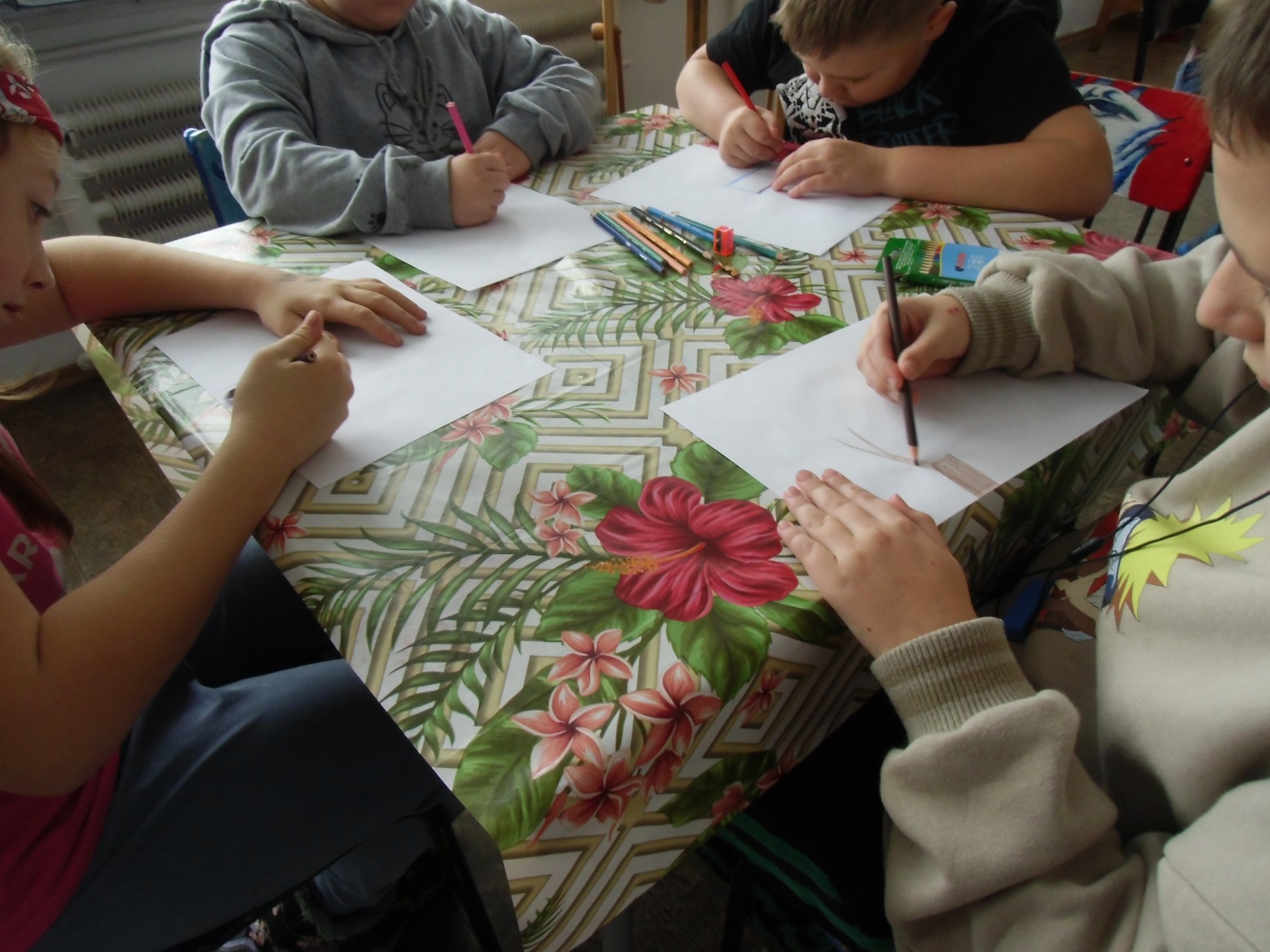 Dzieci rysują drzewa kredkami przy stoliku. 