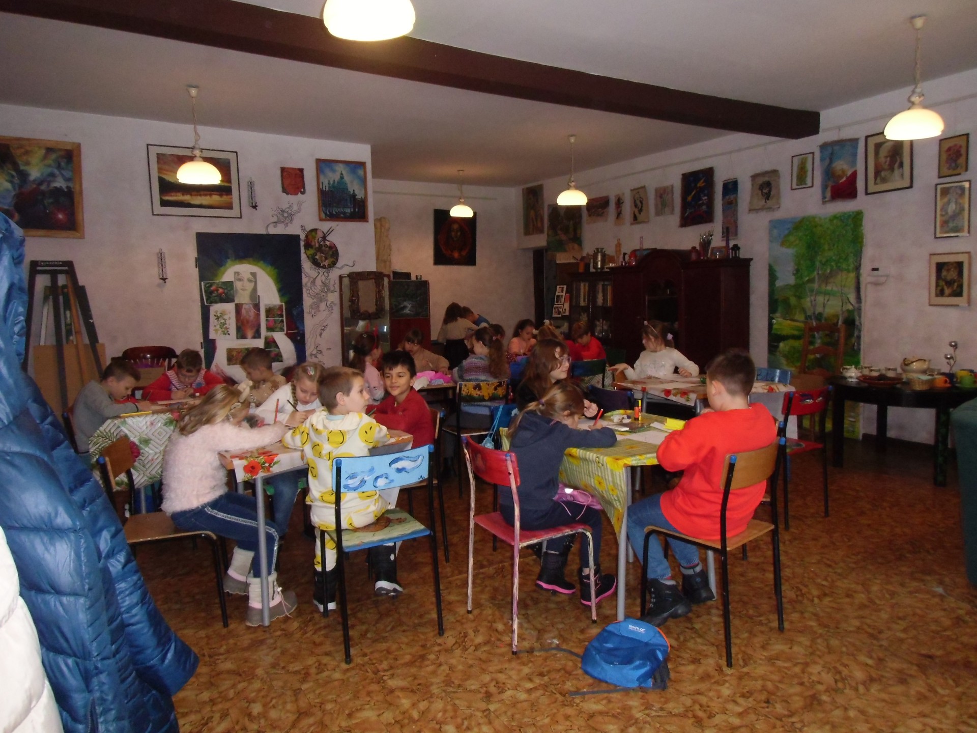 Grupa dzieci siedzi przy stolikach